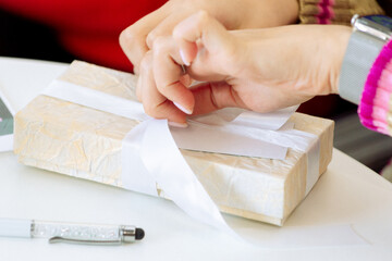 Obraz premium woman ties a ribbon on a gift