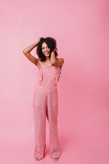 Full-length shot of smiling African young woman. Model straightens her curly hair on isolated background