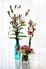 Beautiful blooming carnations in a vase on wooden background