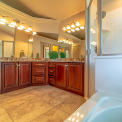 Square frame Bathroom interior with marble countertop brown wood cabinets and large mirrors