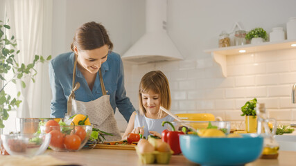 In Kitchen: Mother, Cute Little Daughter Cooking Together Healthy Dinner. Mother Teaches Little Girl Healthy Habits and how to Cut Vegetables for Salad. Cute Child Helping Her Beautiful Caring Parents