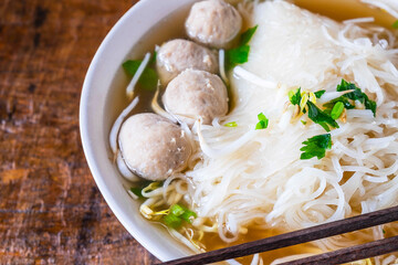 .Noodle and meatballs in a bowl on a wooden table