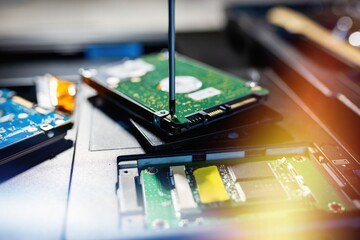 Replacing or installing a hard drive with a screwdriver on an old laptop, on a black background...