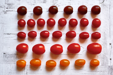 five types of cherry tomatoes on a light wooden background from above close up