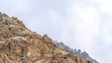 Fototapeta na wymiar Panorama Snow dusted terrain of the rocky Prvo Canyon in Utah with cloudy sky background