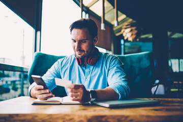 Cropped image of male entrepreneur dressed in blue stylish shirt sitting at wooden table 