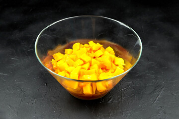 Chopped pumpkin, pieces in a deep transparent glass bowl on black table. pumpkin (butternut squash) in salad dish. Cooking vegetable food