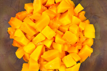 Pumpkin pieces in a deep transparent glass bowl, top view. Chopped pumpkin (butternut squash) in salad dish