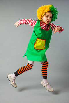 Cute kid clown in a costume and clown wig. April fool's day celebration.