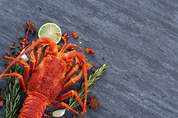 Cooked boiled lobster, delicious dinner seafood meal set with knife and fork on black stone slate background, restaurant menu design, top view, overhead