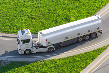 Powerful heavy white truck with a tank for flammable liquids rides turn on the road, close up view.