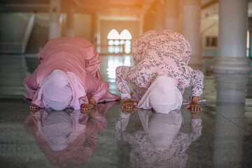 Hands of two muslim woman on the reflection floor praying in traditional clothes.