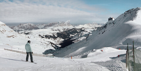 A girl on a snowboard pulls off the mountain towards the villages Corvara and Colfosco. Dolomite Alps (Sella Ronda). Italy.
