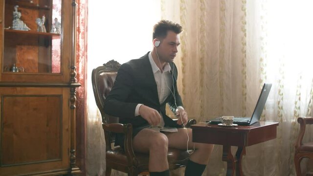 half-dressed businessman in a suit on his upper body, leading a video linking through a computer from home