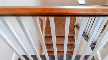 Panorama U shaped staircase with white baluster brown handrail and carpet on treads