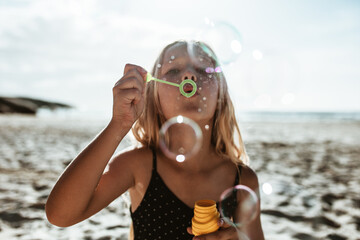 Girl blowing soap bubbles on the beach