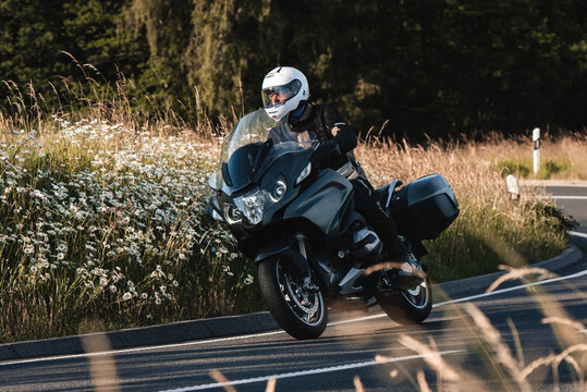 Motorradfahrer f&auml;hrt mit seiner Tourenmaschine durch den Sonnenuntergang