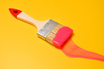 Shot of a brush with pink sticky slime on yellow background. Minimalism in photography, concept creative picture.