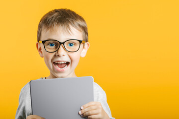 Happy child boy  holding a tablet ipade for your information on the blue background