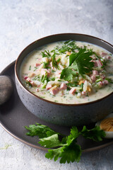 Traditional Russian cold okroshka soup served in a plate with herbs Kefir vegetable soup