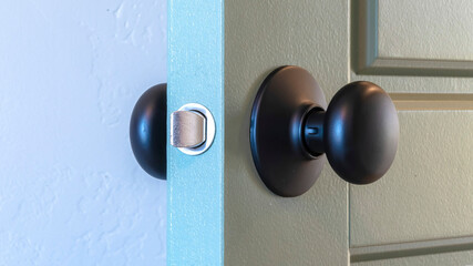 Panorama frame Close up of a round black door knob installed on a gray paneled interior door