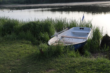 Naklejka na ściany i meble vintage boat with paddle at lake shore