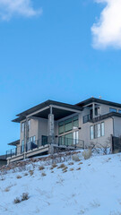 Vertical frame Facade of home on snowy mountain setting against blue sky and clouds in winter