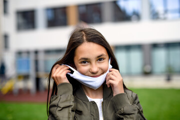 Fototapeta premium Portret szczęśliwego dziecka z maską wraca do szkoły po zamknięciu COVID-19.