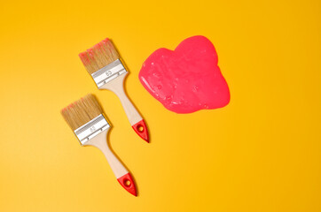 Shot of a brush with pink sticky slime on yellow background. Minimalism in photography, concept creative picture.