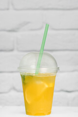 summer refreshing lemonade in a takeaway cup against a white brick wall