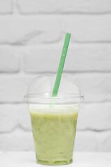 summer refreshing lemonade in a takeaway cup against a white brick wall