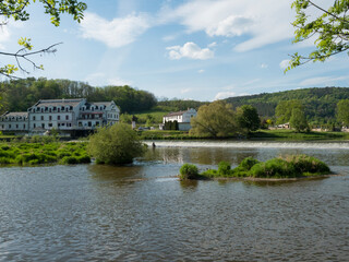 Obraz premium View on the river Berounka in village Zadni Treban with weir and building of Hotel Mlyn Karlstejn, sunny summer day, Czech Rupublic