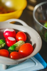 Various coloured organic vegetables washed in colander in kitchen