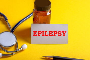 On a yellow background a stethoscope, pen and business card with the inscription EPILEPSY