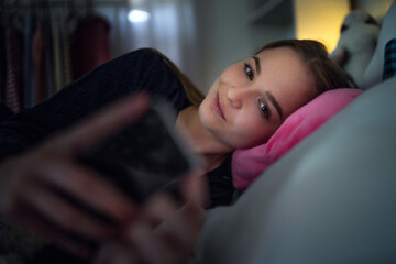 Happy young girl smiling and taking selfie on bed, online dating concept.