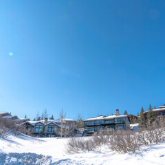 Fototapeta na wymiar Square crop Houses on snowy hill terrain in Park City Utah with clear blue sky background