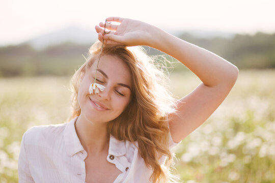 Young beautiful woman relaxing in chamomile field.