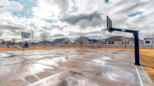 Panorama Basketball courts with neighborhood houses background under blue sky and clouds