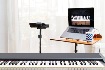 Online piano lessosn setup with a laptop, a piano keyboard and a smartphone on a gimbal as camera. Home environment..