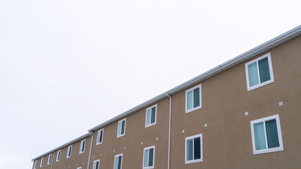 Panorama Back view of townhouses with snowy roofs against overcast sky in winter