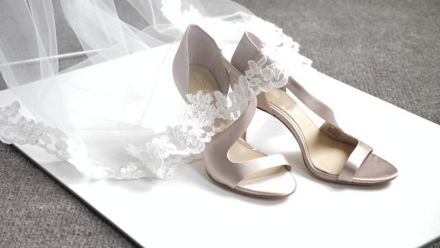 Close Up of White Bridal Shoes Under The Ends of Bride's Dress