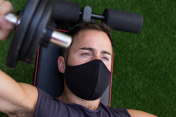 Chico joven entrenando en casa con mascarilla