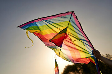Bright multi-colored kite in a woman's hand against the sky.