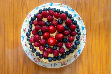 A cake decorated with butter icing and summer fruits including strawberries, raspberries and blueberries.