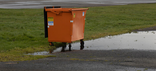 Isolated, open orange dumpster in abandoned industrial area