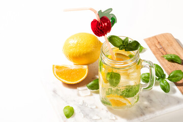 Citrus lemonade or mojito cocktail with lemon and orange and basil. Cold beverage or drink with ice on marble cutting board