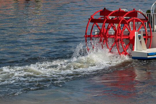 Red paddle wheel on a boat churning the water