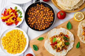 Tortilla tacos with chickpeas, bell peppers, corn, tomatoes, basil leaves, green chilli topped with...