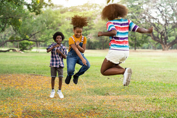 Children are playing sports happily.. Group of African American children having fun jumping over...