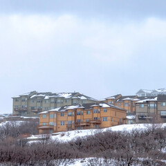 Fototapeta na wymiar Square crop Hill with homes on its gentle slope covered with fresh snow during winter season